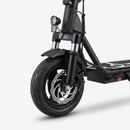 Close-up of the front portion of a black electric scooter with a front suspension fork, disc brake, tire, and headlight on a light gray studio background.