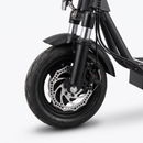 Close-up of the front wheel and suspension of a black electric scooter on a light gray studio background.