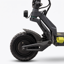 Close-up of a carbon fiber electric scooter showing the front wheel, handlebar, suspension, and part of the deck with a bright yellow accent against a light gray background.